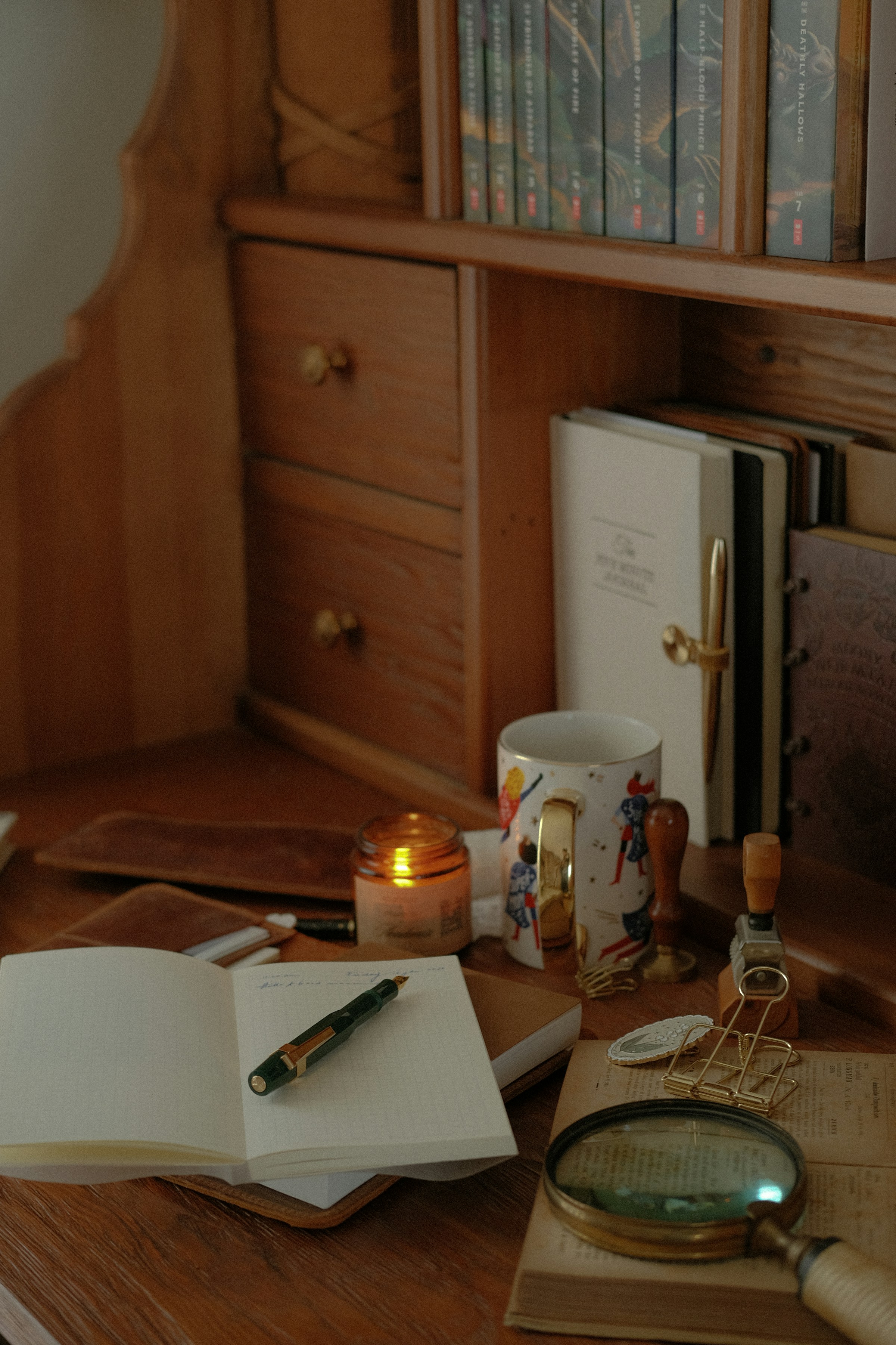 An open journal, pen, and candle on a warm wooden desk — a calm planning moment.